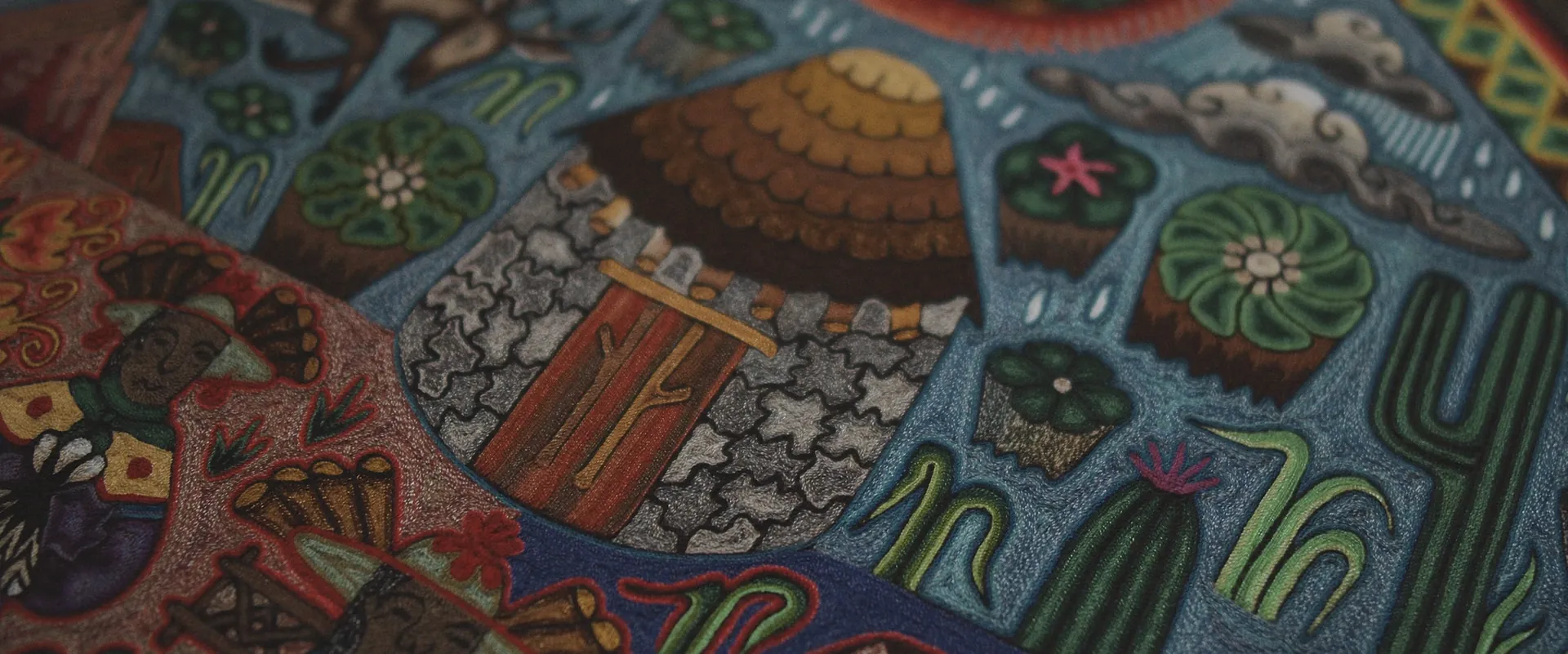 Detail of a yarn painting with cacti, shells and clouds
