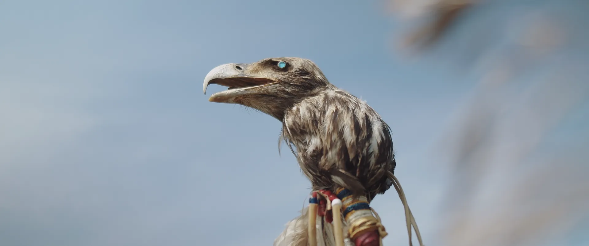 Eagle-head staff with a turquoise eye against a blue sky
